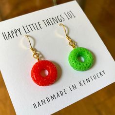 a pair of colorful earrings sitting on top of a piece of paper with the words happy little things 101