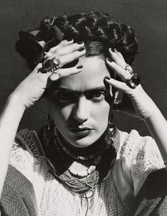 a black and white photo of a woman with her hands on her head, wearing rings