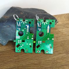 pair of green circuit board earrings sitting on top of a wooden table next to a rock