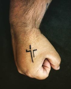 a hand with a cross tattoo on it