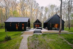 two black cabins in the middle of a forest