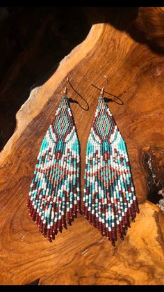 a pair of earrings sitting on top of a piece of wood