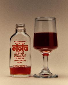 a glass and bottle sitting next to each other on a white surface with a brown background