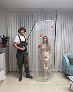 a man standing next to a woman holding a fishing pole in front of a fish net