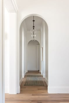 an empty hallway with white walls and wood floors