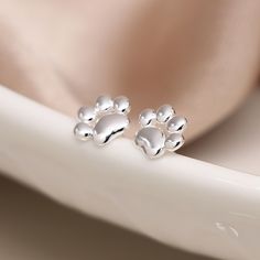 These cute cat paw earrings are a sweet design in sterling silver, gorgeously detailed with a polished finish. These dainty silver cat paw print stud earrings feature a classic butterfly and post fastening and are suitable for almost any age. A really lovely gift for children, bridesmaids, best friends or cat lovers. Versatile and easy-to-wear, our stunning earrings shine when worn on their own or will add some sparkle to your stacked earring look in a second or third piercing. A wonderfully tho Sterling Silver Jewelry With Cat Print, Cute Cat Design Adjustable Earrings, Tiny Paw Print, Silver Cat Design Drop Earrings, Paw Print Earrings, 13th Birthday Gifts, Silver Cat Design Dangle Earrings, Cat Paw Print, Cat Earrings Studs