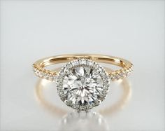 an engagement ring with a round brilliant diamond surrounded by pave set diamonds in yellow gold