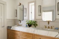 a bathroom with marble counter tops and two mirrors on the wall next to each other