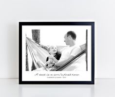 a black and white photo of a man holding a baby in a hammock