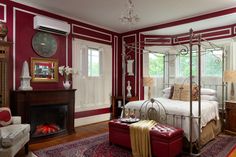 a bedroom decorated in red and white with a canopy bed next to a fire place