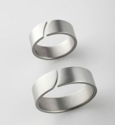 two silver rings sitting next to each other on a white surface with one ring in the middle