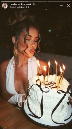 a woman sitting in front of a white cake with lit candles