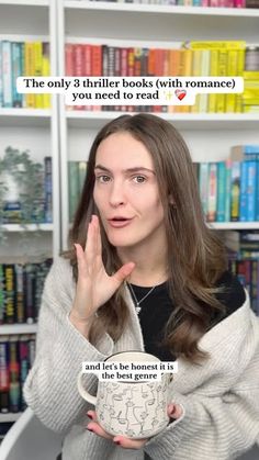 a woman is holding a coffee cup in front of bookshelves