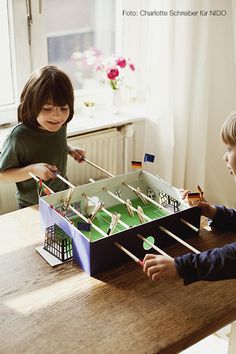 two young children playing with a table top soccer game