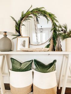 a white table topped with lots of pillows and plants next to a round mirror on top of a wall