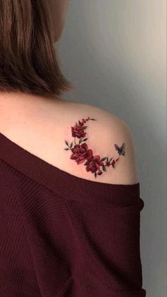 a woman's shoulder with red roses and butterflies on it