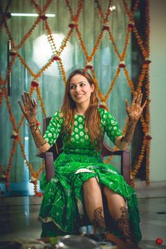 a woman in a green dress sitting on a chair with her hands up to the side