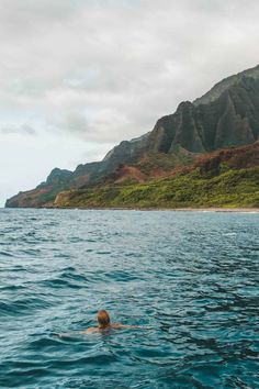 a person swimming in the ocean with mountains in the background