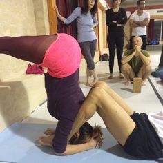 a group of people doing yoga poses in a room with one woman on the floor