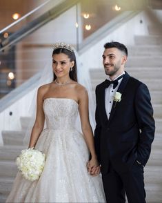 a bride and groom holding hands in front of stairs