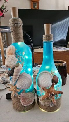 two bottles with seashells and starfish in them are sitting on a table