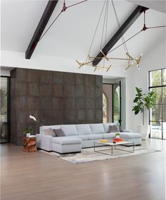 a modern living room with wood flooring and large sectional couch in front of a stone wall