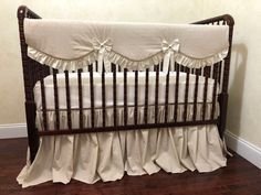 a baby crib with white ruffles and bows on the bed skirting