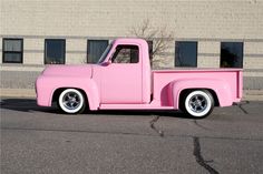 a pink truck parked in front of a building