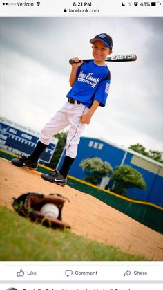 a young boy holding a baseball bat standing on top of a dirt field next to a catchers mitt