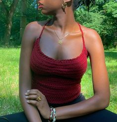 a woman sitting in the grass wearing a red top