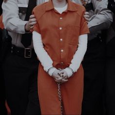 a woman in an orange prison uniform is being held by two men with their hands on her hips