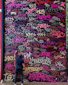 a man standing in front of a large wall covered with lots of grafitti