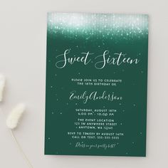 a green and white wedding card with the words sweet sixteen on it, next to some flowers