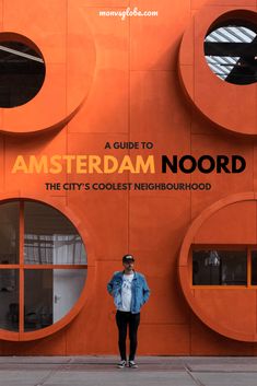 a woman standing in front of an orange building with round windows and the words amsterdam noordd on it