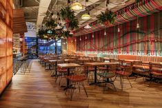 an empty restaurant with wooden tables and colorful striped wallpaper on the walls, along with hanging plants