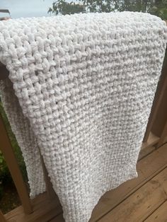 a white crocheted blanket on a wooden deck