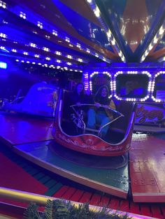 two people ride on a roller coaster at an amusement park in the dark with blue lights