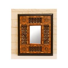 an ornate wooden mirror mounted on a wall next to a white brick wall with a black frame