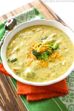 a white bowl filled with broccoli cheese soup on top of a green napkin