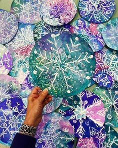 someone is painting snowflakes on paper with blue and purple colors in the background