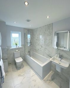 a white bathroom with marble walls and floors