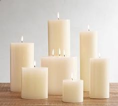 several white candles sitting on top of a wooden table