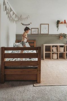 a young child standing on top of a wooden bed