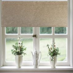 three white vases with flowers are sitting on a window sill in front of the blinds