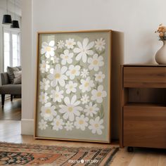 a white and yellow flowered painting on a wall next to a dresser