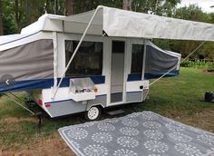 a camper trailer is parked in the grass with a cover on it's roof