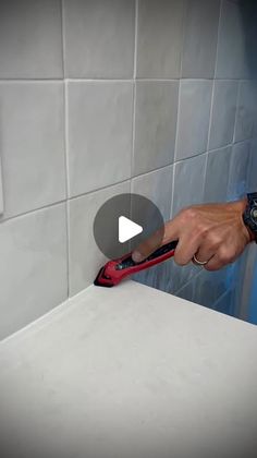 a man is using a pair of scissors to cut tile on the wall in his bathroom