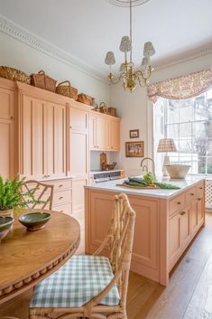 a kitchen with pink cabinets and an island in the center is filled with green plants