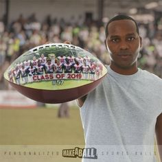 a man is holding a football in front of a large group of people on the field