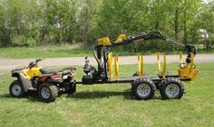 an atv is parked in the grass next to a small truck with a crane on it